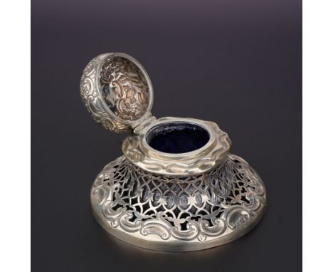 Victorian silver inkwell of circular form, hinged cover and blue glass liner, pierced sides above scrolls D12cm Birmingham 18