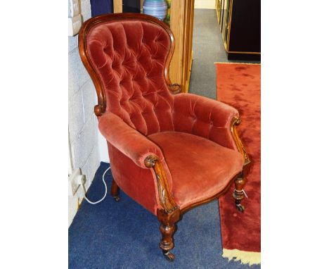 A Victorian mahogany framed button back armchair, the moulded framed back over scroll arms, terminating in acanthus carving, 