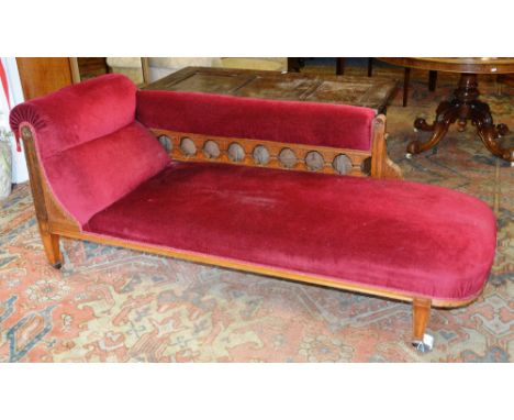A late Victorian oak chaise lounge, the cushioned end and balustrade scrolling from left to right, with cushioned seat raised