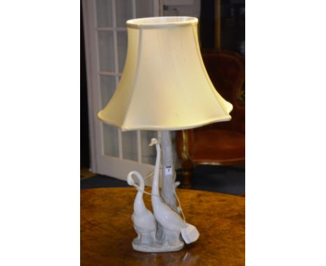 A Nao Porcelain table lamp, in the form of two swans standing next to a tree trunk, with shade, 70cm high