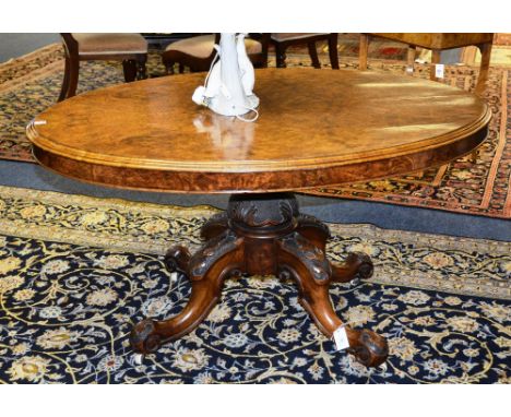 A Victorian burr walnut loo table, the moulded oval tilt top raised on foliate carved baluster column, quad cabriole legs ter