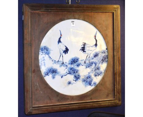 A Chinese blue and white ceramic wall panel, depicting storks in foliage, with character marks on white ground, in wooden fra