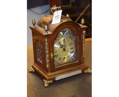 A Georgian style moonface mantle clock by Warmint, the arched case mounted by handle and acorn finials, with metal face, Roma