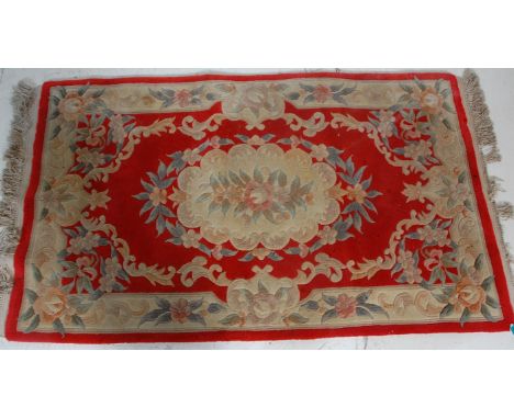 A vintage, believed early 20th Century Chinese floor rug having a red ground with floral works and tasseled ends. 91cm x 170c