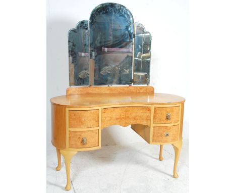 An early 20th Century Art Deco walnut dressing table of kidney shaped form having adjustable mirrors and hidden central drawe