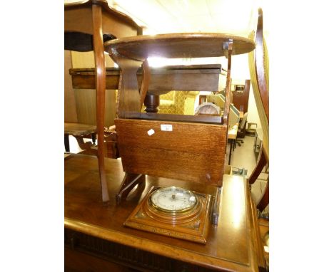 AN OAK OVAL COFFEE TABLE AND PERIODICAL RACK COMBINED AND AN ANEROID BAROMETER IN A CARVED OAK SQUARE CASE 