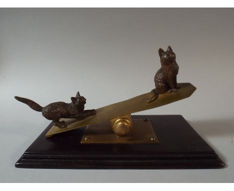 A Novelty Desk Top Paper Clip in the form of Two Cats Playing on Seesaw. On Mahogany Plinth. 18x10cm