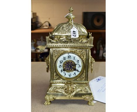 A 20TH CENTURY BRASS MANTEL CLOCK, the heavily cast case with urn shaped finial on domed top, the square case with enamel cha