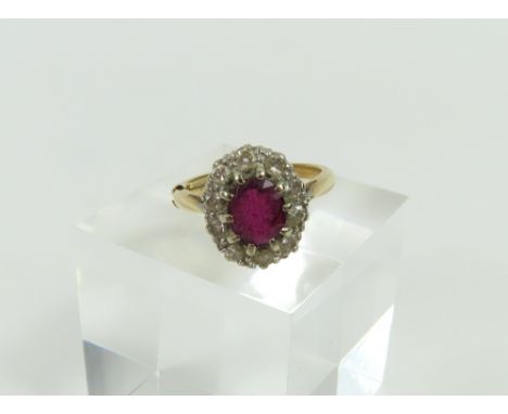 A ruby and diamond cluster ring, the oval shaped ruby claw set with a row of diamonds around it, finger size K, marked '18ct'