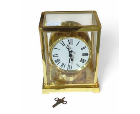 A Jaeger le Coultre Atmos square brass carriage clock upon bracket feet. Features glass panels around the body, in which sits
