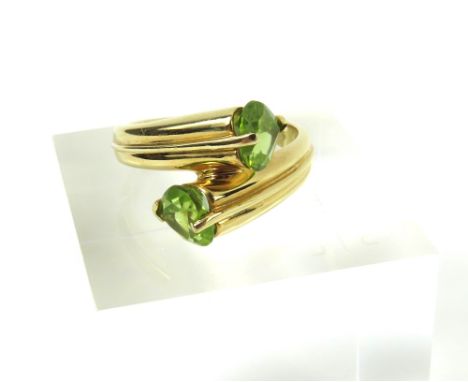 A peridot dress ring, the two heart shaped peridots in a cross over, marked '14k', finger size K, 4.42g gross