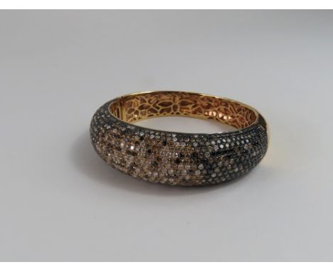 A multi coloured diamond set bangle, one half of the bangle set with round cut white, grey, brown and black diamonds, marked 