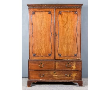 A George III Figured Mahogany Linen Press, the upper part with moulded cornice, blind fret and leaf carved frieze, fitted thr