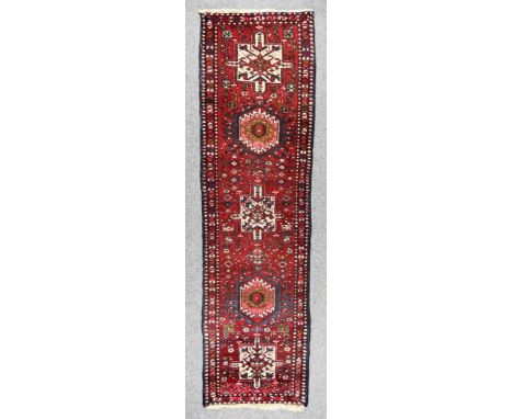 A 20th Century Hamadan Runner woven in colours of ivory, navy blue and wine, with three stylised cross medallions intersperse