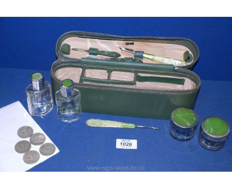 A green leather oblong Vanity case with green enamel contents, bottles, files plus five two-shilling pieces.