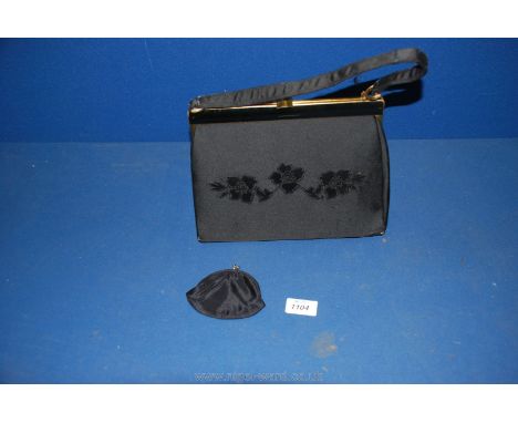 A black ladies Handbag having embossed roses to the front of the bag and having a small coin purse inside (the corners of the