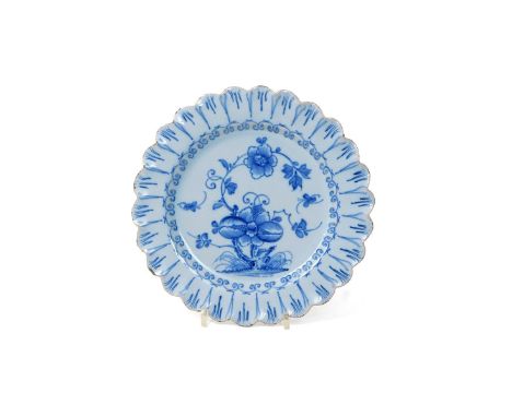 A delftware scallop-edged plate  c.1760-70, painted in blue in the Chinese manner with an insect flying around a large spray 
