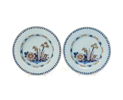 A pair of delftware plates  c.1760, decorated in polychrome enamels with sprays of bamboo and peony in shades of blue, green,