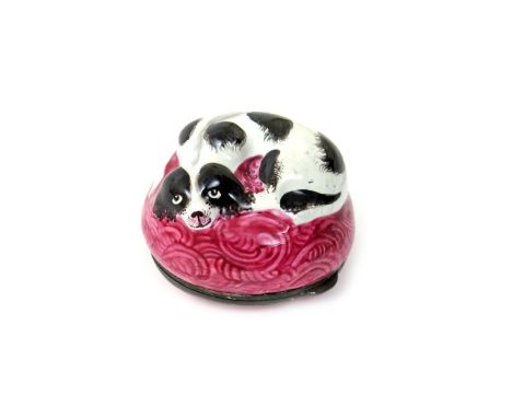 An English enamel bonbonnière  c.1770-80, modelled as a black and white spaniel curled up on a patterned pink cushion, the hi