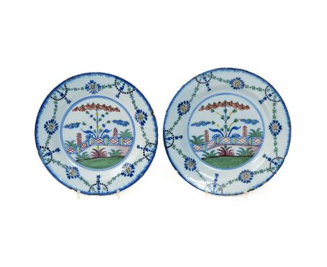 A pair of delftware plates  c.1770, probably Lambeth, painted in polychrome enamels with tall plants issuing from a red, blue