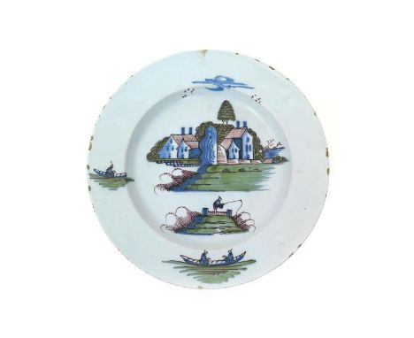 A large Bristol delftware charger  c.1760-70, brightly enamelled in blue, red, manganese and green with a typical landscape, 