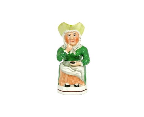 A rare female Snuff Taker Toby jug c.1830, wearing a green dress with a polka dot scarf tied around her neck, holding a circu