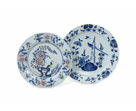 Two delftware chargers  mid 18th century, the smaller painted in polychrome enamels with a peacock perched on holey rockwork 