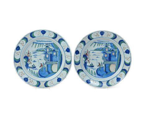 A large pair of Bristol delftware chargers  mid 18th century, decorated in red, green and blue with a standing figure fishing