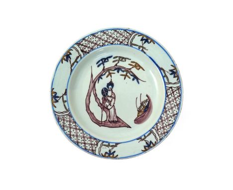 A Bristol delftware plate  mid 18th century, painted predominantly in manganese with a Chinese lady seated on a large bamboo 