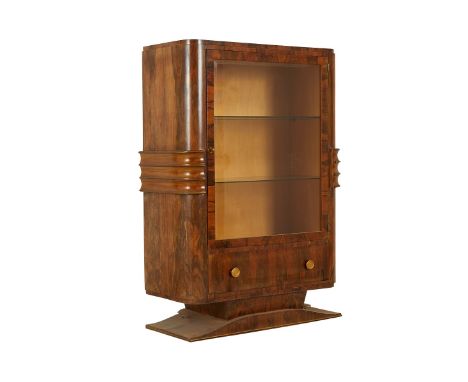 Art Deco wooden cabinet with glass shelves. On a pedestal base with two glass shelves and a lower drawer.Provenance: From the