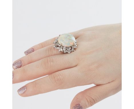 18k white gold, opal, and diamond ring. The ring is set with one large 10.65 carat oval cabochon cut opal. The opal is surrou