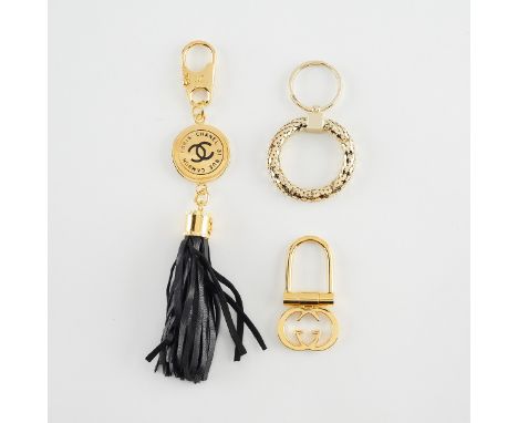 Group of three luxury brand keychains including:Chanel, Paris. One gold-tone metal keychain with black leather tassels.Gucci,