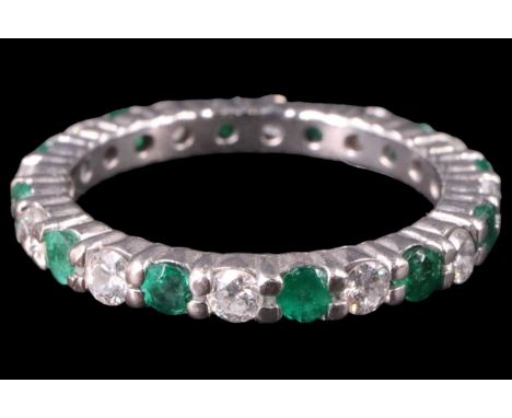 A contemporary diamond and emerald eternity ring, having 12 brilliant cut diamonds (approximately 0.6 carats aggregate weight