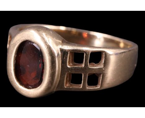 A contemporary Macintosh-influenced garnet finger ring, having an oval of approximately one carat set in a bezel between pier