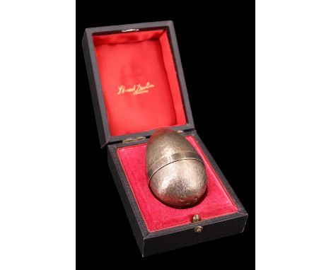 A cased 1970s Stuart Devlin silver gilt 'Surprise' egg having a textured exterior and slip-fit lid revealing a bouquet of ena