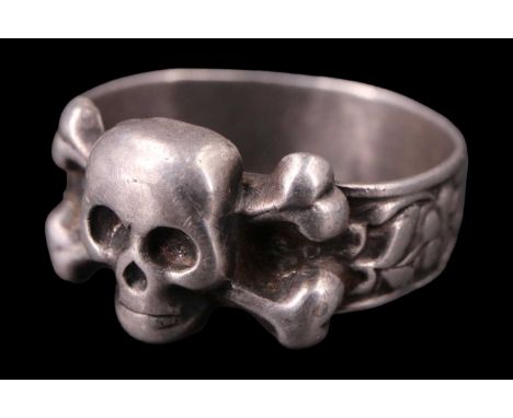 An early 20th Century Russian white metal ring, being a floral relief band faced with a skull and cross-bones device, bearing