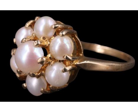 A 1970s daisy set pearl ring, having a 5 mm pearl set above a surrounding annulus of six 4 mm pearls, between tapering should