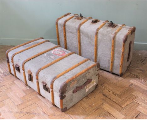 Two vintage canvas and leather steamer travelling trunks with luggage labels 