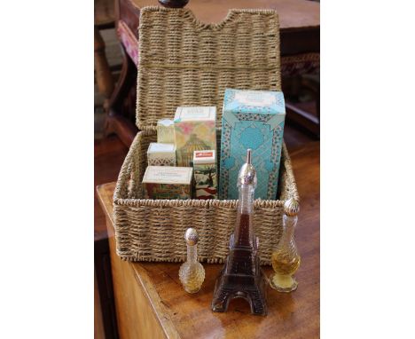 A wicker basket containing vintage boxed and unboxed Avon perfumes including Petite Telephone eau de cologne, Bird in a Cage,