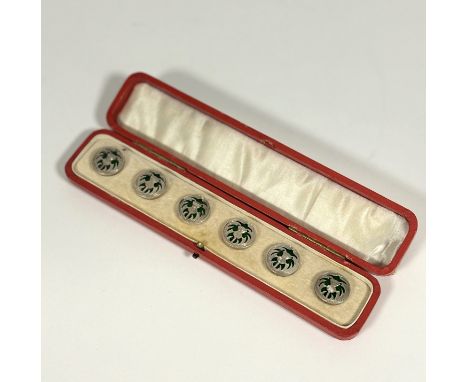 A cased set of six white metal and green enamel buttons, early 20th century, each circular, modelled with a thistle and leave