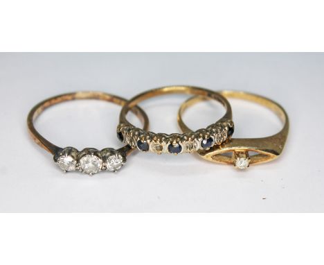 A group of three rings comprising a three stone diamond ring marked 'PLAT', a hallmarked 9ct gold diamond and sapphire ring a