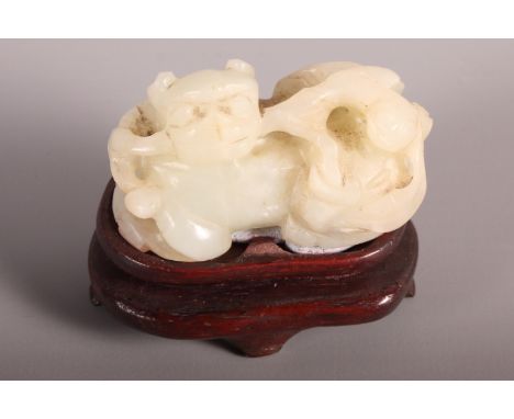 A carved jade lion, on hardwood stand, 2" wide