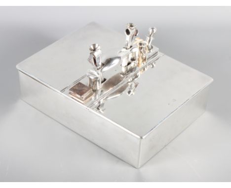 A silver table cigar box with central handle, fitted two cigar cutters, match box and lighter