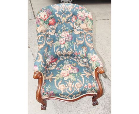 A 19th Century mahogany framed button back armchair, upholstered in a floral print fabric, with scroll carved terminals and s