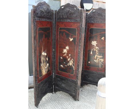 A 19th Century oriental carved hardwood framed screen, inset four red and black lacquered panels inlaid birds and flowers in 