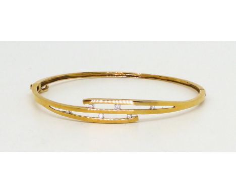 A 9ct gold diamond set bangle, set with estimated approx 0.07cts of brilliant cut diamonds in a pretty scattered configuratio