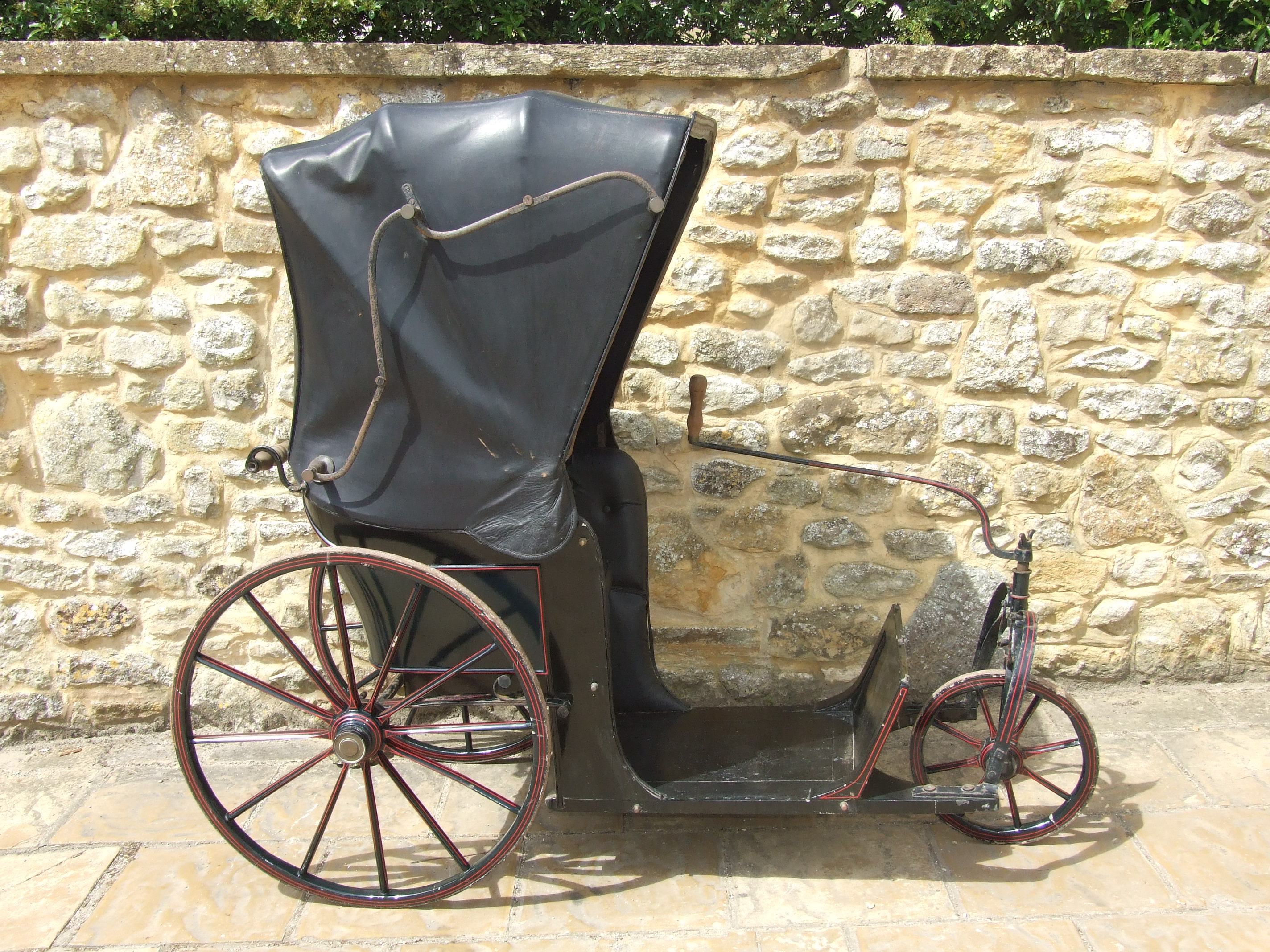 A Victorian bath chair, with tilter steering, faux pram hood and black