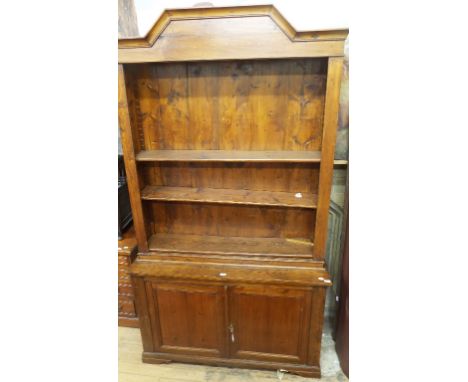 A pine cabinet, having a bookcase top above a pair of panel doors, on bracket feet, 138 cm wide