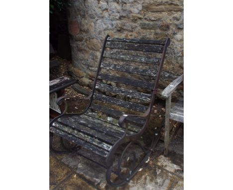 A cast iron rocking garden armchair, with wooden slats, a two seater garden bench, and another similar (3)