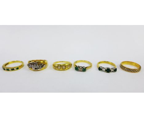 A collection of six 18ct gold rings to include a five stone diamond ring, three emerald and diamond rings, a wedding band and